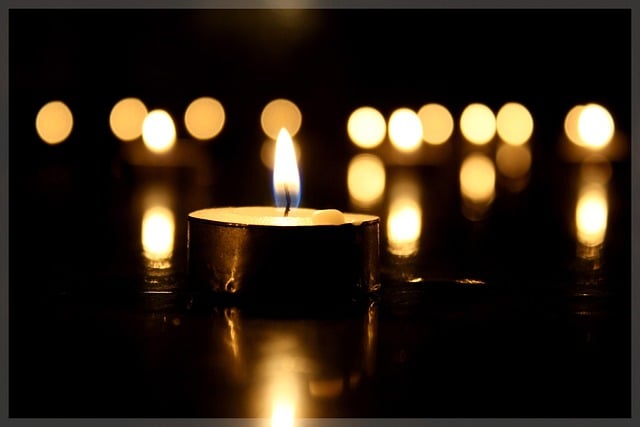 Single memorial candle glowing softly in the foreground with warm lights behind, symbolizing reflection and togetherness through Orange City, FL cremations.