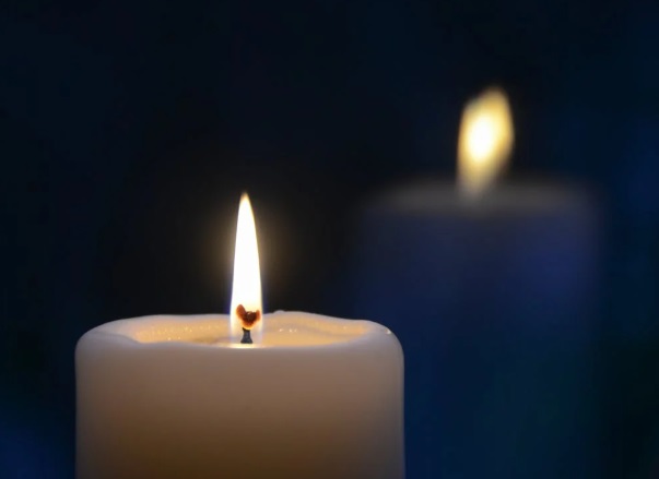 White candle with soft glowing flame in a peaceful setting for Orange City, FL cremation services.