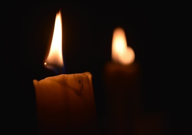 Two candles with gentle flames in a dark setting, creating a calm memorial atmosphere in DeLand, FL.